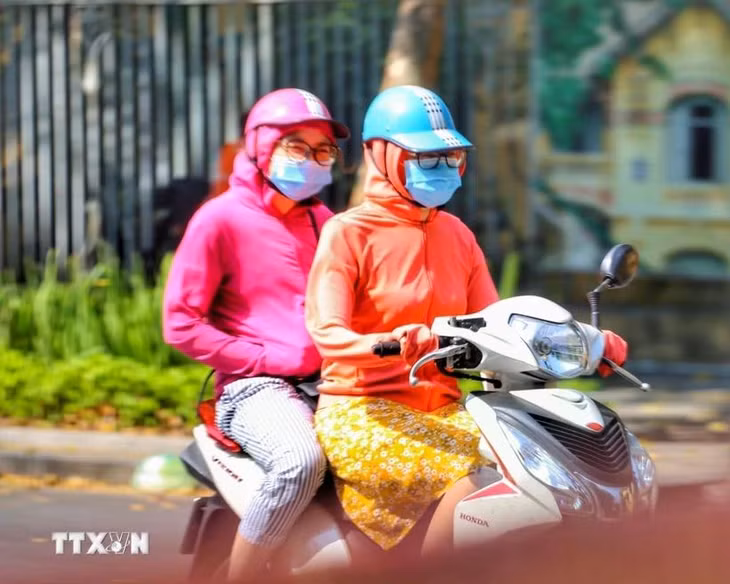 Người ra đường luôn mặc áo chống nắng để tránh sốc nhiệt. (Ảnh: Tuấn Đức/TTXVN)