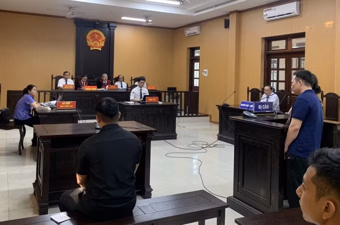 Bị cáo Trương Đình Nhạt (áo xanh, phải) tại tòa, shipper Lâm Anh Đạt ngồi bên trái (áo đen). Ảnh: Hương Trà