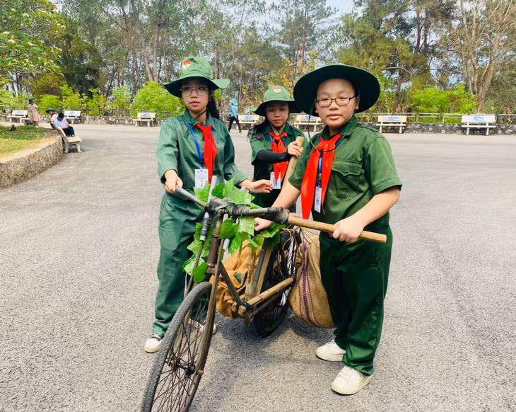 Các em tham gia trải nghiệm hóa thân thành những chiến sĩ quân đội đẩy xe đạp thồ trên đoạn đường dốc.