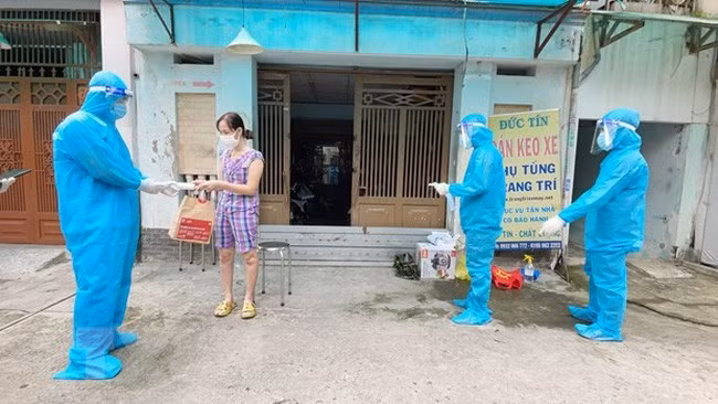 Nhân viên y tế trạm y tế lưu động phường 25, quận Bình Thạnh phát túi thuốc cho F0 điều trị tại nhà. (Ảnh: Đinh Hằng/TTXVN)
