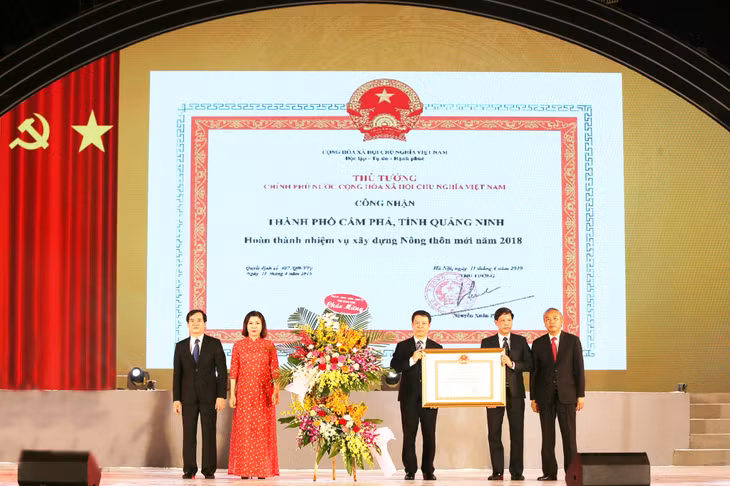 Thừa ủy quyền của Thủ tướng Chính phủ, đồng chí Phùng Đức Tiến, Thứ trưởng Bộ NN và PTNT đã trao Bằng công nhận thành phố hoàn thành nhiệm vụ xây dựng nông thôn mới cho TP. Cầm Phả (6-2019). Ảnh PV