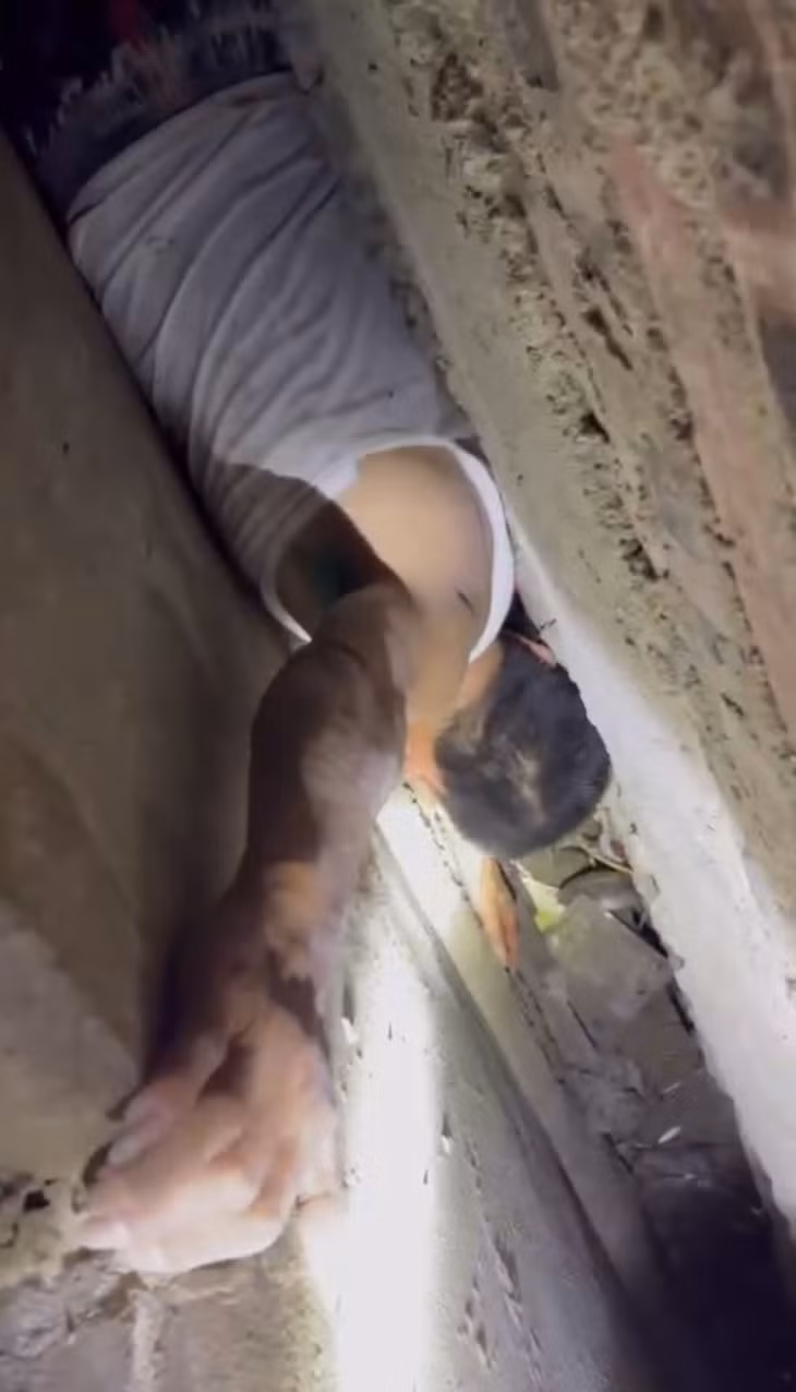 Hình ảnh ông S. bị mắc kẹt giữa tường nhà. Ảnh: Cắt từ clip