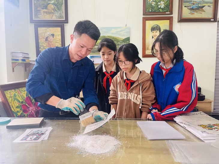 Thầy giáo Đinh Công Tuyến hướng dẫn nhóm học sinh thực hiện dự án Phóng tác tranh dân gian Đông Hồ trên chất liệu bột điệp.
