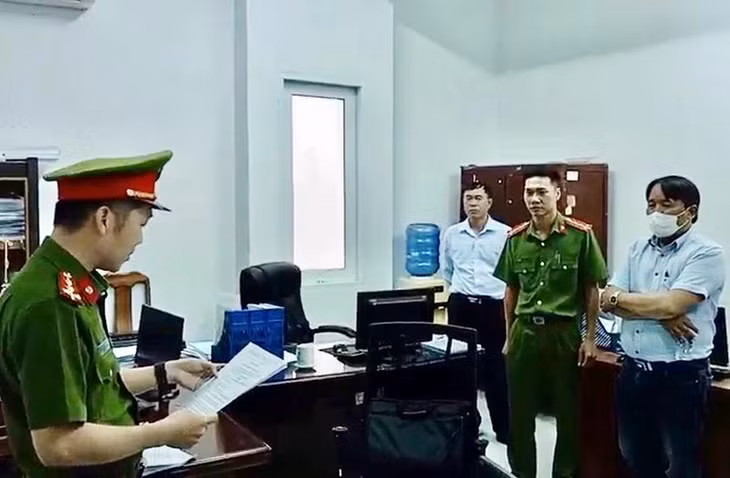 Trần Hữu Dũng (khoanh tay) nghe lệnh bắt bị can từ cơ quan chức năng.