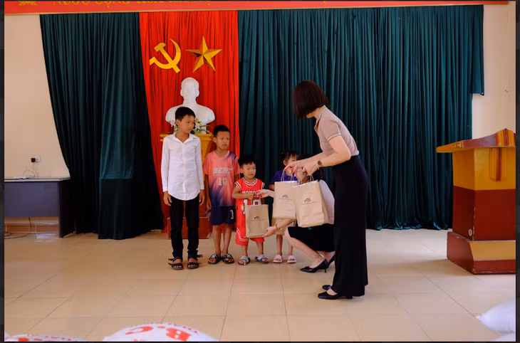 Bà Vũ Thị Mơ (bên phải) - Giám đốc vận hành Khối khách sạn Tập đoàn Paradise Vietnam trao quà tặng là đồ dùng học tập cùng nhu yếu phẩm cho trẻ em trong gia đình có hoàn cảnh khó khăn tại xã Bằng Cả.