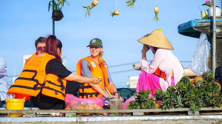 Du khách nước ngoài thưởng thức trái cây ở chợ nổi Cái Răng, Cần Thơ. Chợ nổi Cái Răng là điểm dừng phổ biến của khách quốc tế du lịch Việt Nam. Ảnh: Tạ Quang