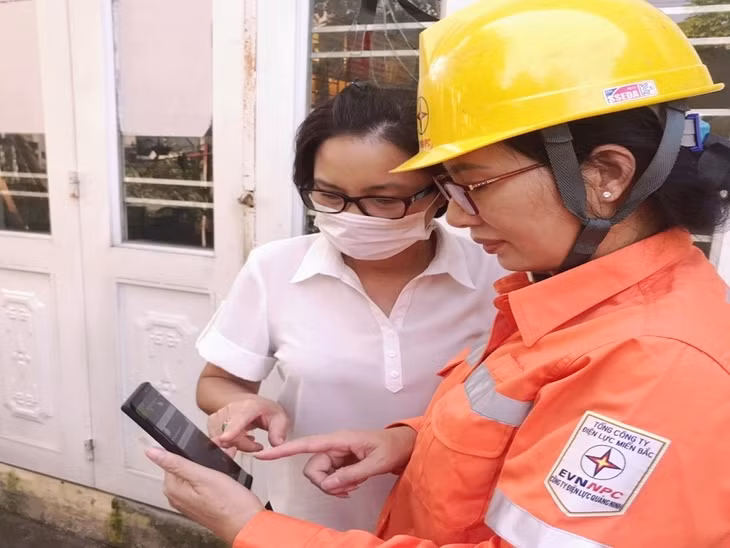 Công nhân Điện lực TP Hạ Long hướng dẫn khách hàng sử dụng App chăm sóc khách hàng.
