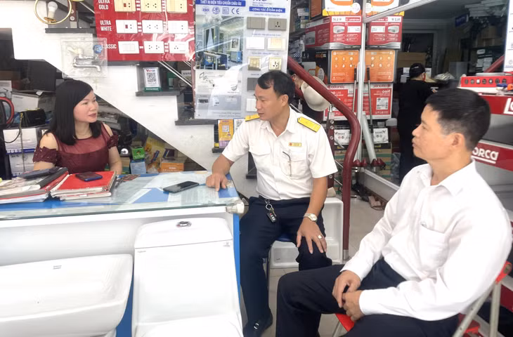 Cán bộ Chi cục Thuế khu vực Cẩm Phả - Vân Đồn - Cô Tô tuyên truyền tới các hộ kinh doanh trên địa bàn TP Cẩm Phả thực hiện chuyển đổi số trong quản lý thuế. Ảnh: Thu Trang