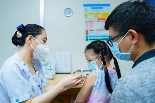 Bé gái được bố đưa tới bệnh viện tiêm vaccine phòng cúm. Ảnh: BVĐHYD TP.HCM.