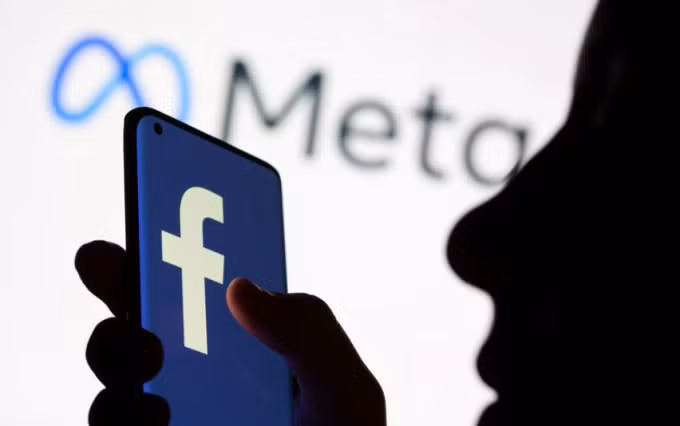 Một phụ nữ cầm smartphone với giao diện Facebook. Ảnh: Reuters