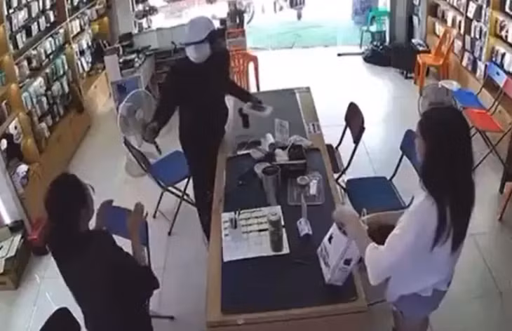 Tên cướp cầm vật nghi là dao ra dọa nhân viên cửa hàng và khách đến cửa hàng để cướp tài sản. (Ảnh cắt từ video).