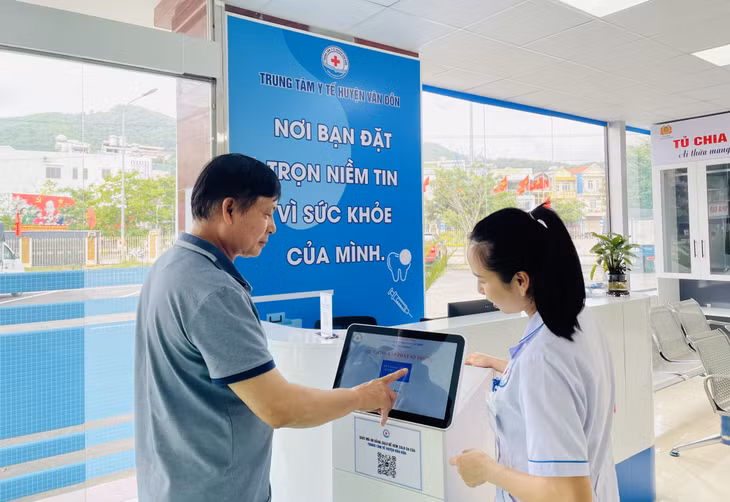 Nhân viên y tế hướng dẫn người dân lấy số thứ tự tự động.