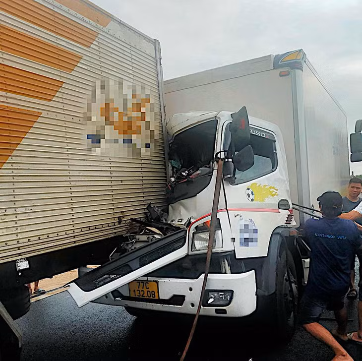 Người đi đường dùng xà beng cậy cửa để cứu người kẹt bên trong xe. Ảnh: Duy Tuấn