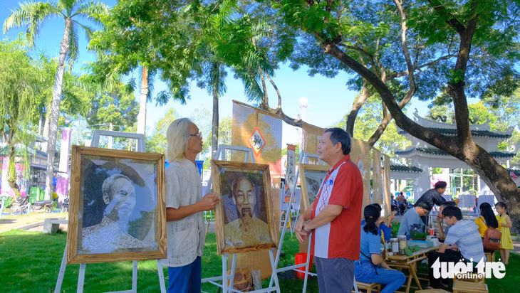 Ông Lê Văn Nghĩa (bìa trái) thuyết minh với khách tham quan triển lãm tranh sen tại Lễ hội sen Đồng Tháp lần thứ 2 - Ảnh: ĐẶNG TUYẾT