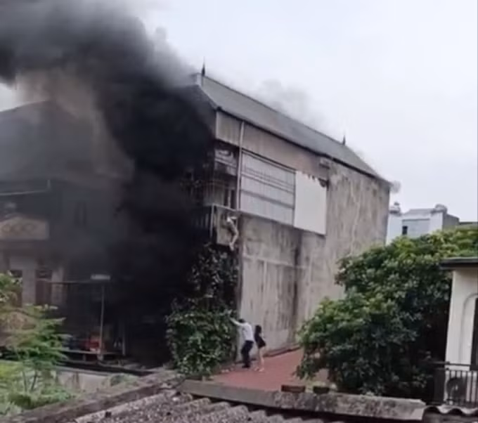 Khói đen bao trùm ngôi nhà, một số người trèo sang nhà bên cạnh để thoát nạn. Ảnh: Cắt từ video
