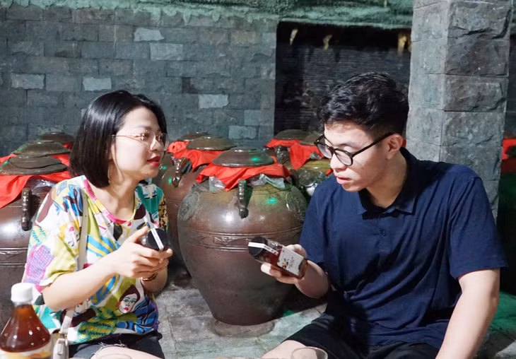 Du khách tìm hiểu về sản phẩm nước mơ Yên Tử do gia đình ông Vũ Anh Tuấn sản xuất khi tới tham quan mô hình tại xã Thượng Yên Công.
