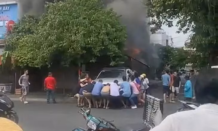 Hàng chục người cùng nhau hô hào, đẩy chiếc xe ô tô tránh khỏi đám cháy nhà. Ảnh: HT
