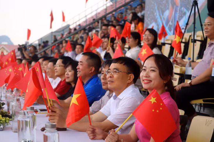 Trên khán đài, các đại biểu cổ vũ cho cầu thủ hai đội.