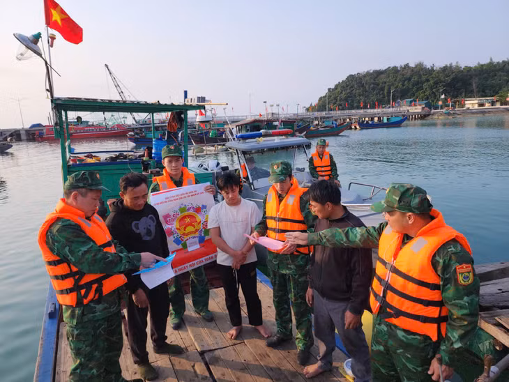 Cán bộ, chiến sĩ Đồn Biên phòng Thanh Lân tuyên truyền, vận động ngư dân đang neo đậu tham gia bầu cử đúng quy định.