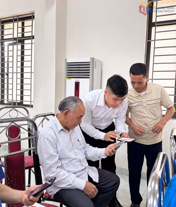 Đảng viên Nguyễn Bá Khải (ở giữa) hướng dẫn người dân trên địa bàn phường cài đặt các ứng dụng trên điện thoại thông minh.
