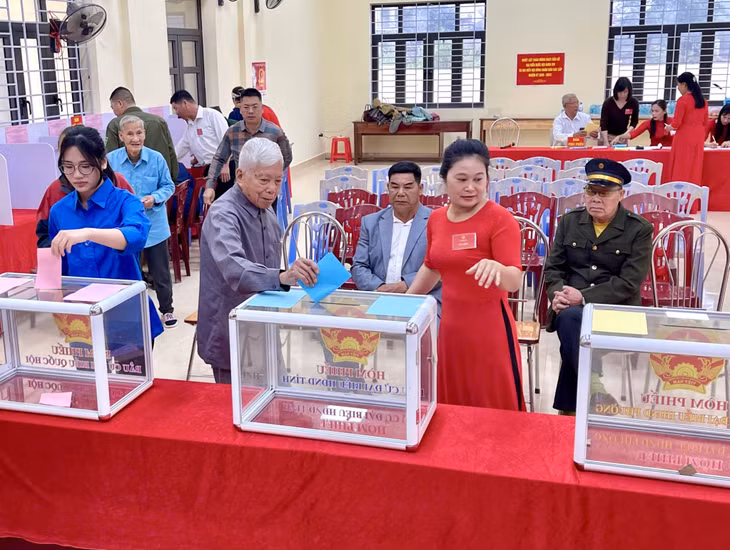 Cử tri Hà Văn Tứ (thứ 2 từ trái sang, 101 tuổi), trực tiếp dự lễ khai mạc và bỏ phiếu tại khu vực bỏ phiếu số 15, khu Đồng Giang, phường Hoành Bồ. Ảnh: Hồng Phương - CTV