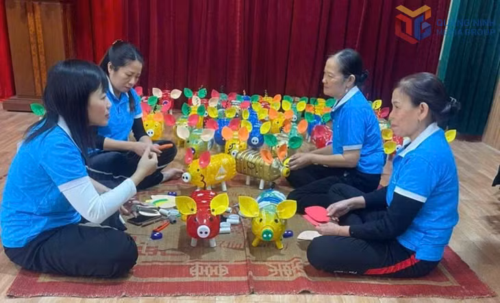 Chị Ngô Thị Tuyết Anh (thứ 2 từ trái sang) cùng hội viên phụ nữ Chi hội Phụ nữ khu Vĩnh Thông (phường Mạo Khê) thực hiện mô hình tái chế can nhựa thành những “chú lợn tiết kiệm” để gây quỹ hoạt động.
