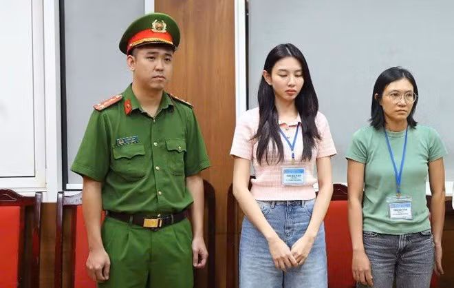 Hoa hậu Nguyễn Thúc Thùy Tiên (giữa) khi bị khởi tố, điều tra tội "Lừa dối khách hàng" và một bị can khác liên quan đến sản phẩm kẹo Kera. Ảnh: Bộ Công an