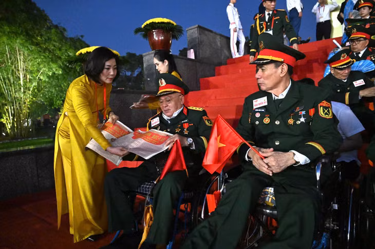 Các đại biểu và cựu chiến binh đến dự Lễ diễu binh, diễu hành trên Quảng trường Ba Đình với phụ san Báo Nhân Dân. (Ảnh TRẦN HẢI)