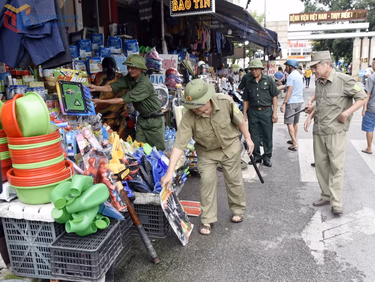 Các thành viên của Tổ Nhân dân tự quản ANTT do CCB làm nòng cốt ở Khu 6, phường Uông Bí nhắc nhở các hộ kinh doanh không lấn chiếm vỉa hè đảm bảo an toàn giao thông tại khu vực cổng Bệnh viện Việt Nam - Thụy Điển Uông Bí.
