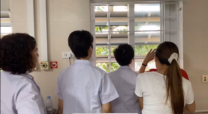 Các bác sĩ ngắm đoàn diễu binh qua cửa sổ trong phòng bệnh. Ảnh: Thùy Linh