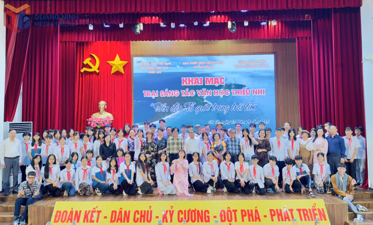 Lãnh đạo Đặc khu Cô Tô, các nhà văn tham gia trại sáng tác và các em học sinh chụp ảnh lưu niệm.