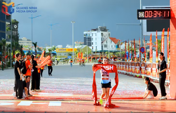 Runner nữ về đích ở cự ly 5km trong tiếng cổ vũ của đông đảo người hâm mộ, hoạt náo viên.