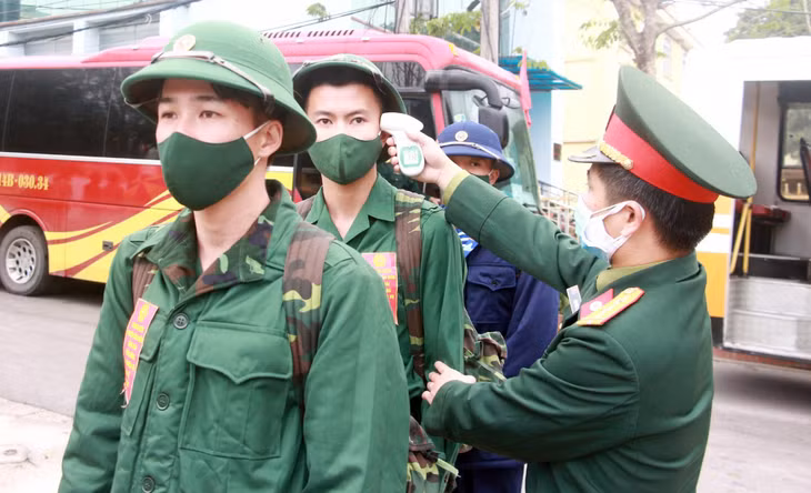 Ban CHQS huyện Vân Đồn thực hiện đo thân nhiệt cho các tân binh trước khi vào khu vực tổ chức lễ giao nhận quân năm 2021.