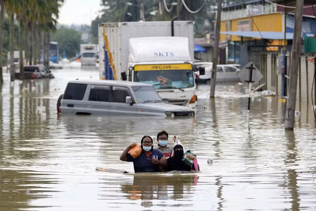 Người dân lội qua con đường ngập nước ở Shah Alam, ngoại ô Kuala Lumpur, Malaysia, ngày 20/12/2021. (Ảnh minh họa: AP)
