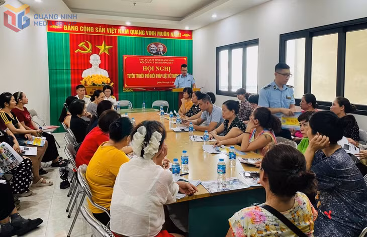 Đại diện Đội QLTT số 5 tuyên truyền pháp luật, phát tờ rơi cho các hộ kinh doanh tại chợ Hạ Long II. Ảnh: Ngọc Trâm