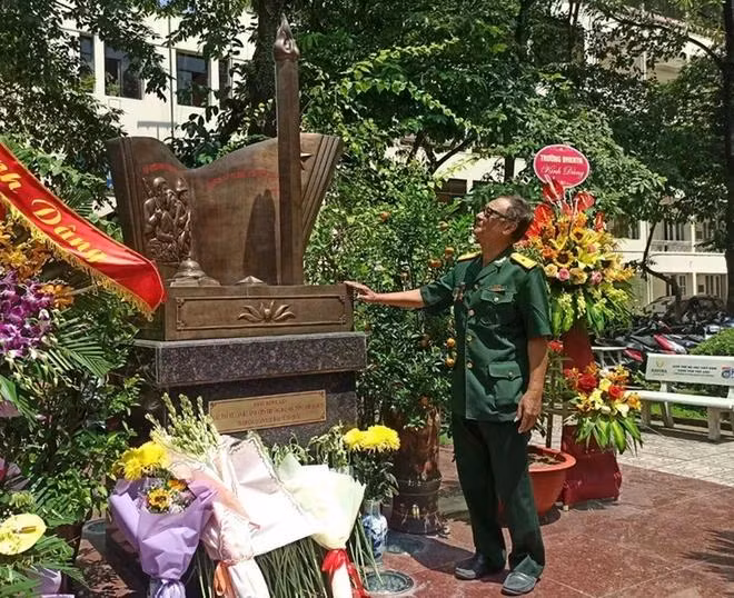 Nhà báo Phùng Huy Thịnh bên đài tưởng niệm tại sân trường Đại học Khoa học Tự nhiên, Đại học Quốc gia Hà Nội. Đây cũng chính là nơi các sinh viên của Đại học Tổng hợp làm lễ xuất quân ra trận ngày 6/9/1971. (Ảnh: PM/Vietnam+)