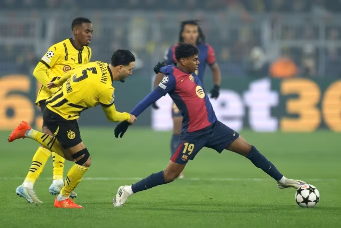 Yamal (phải) đi bóng trong sự truy cản của Bensebaini (số 5), trên sân Signal Iduna Park hôm 11/12. Ảnh: Reuters