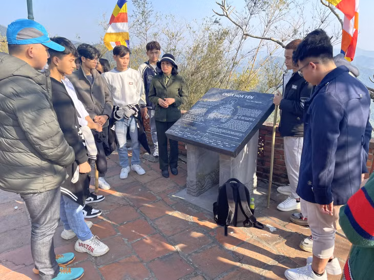 Du khách nghe cán bộ Ban quản lý Di tích và Rừng quốc gia Yên Tử giới thiệu về giá trị di tích khi hành hương về Yên Tử.