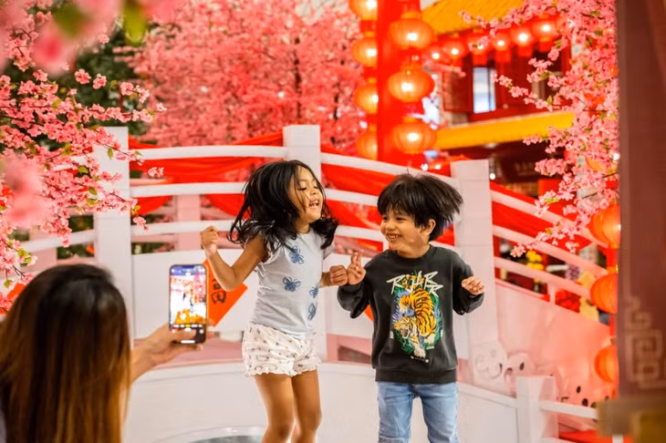 Trẻ em tạo dáng chụp ảnh với đồ trang trí Tết Nguyên đán tại một trung tâm mua sắm ở Kuala Lumpur, Malaysia ngày 18/1. Ảnh: Xinhua