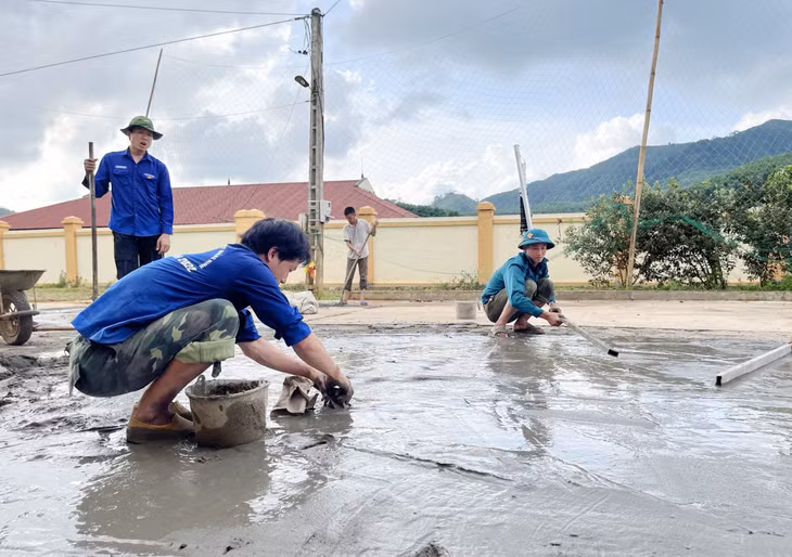 Nguyễn Việt Anh (người ngồi bên trái) cùng đội sinh viên tình nguyện Trường Đại học Công nghiệp Quảng Ninh đổ bê tông sân nhà văn hóa thôn Đồng Loóng, xã Thanh Lâm (Ba Chẽ).