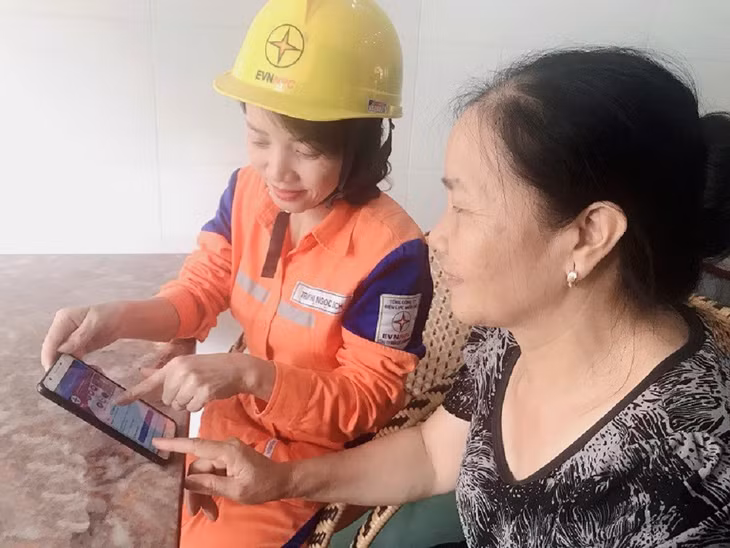 Nhân viên Công ty Điện lực Quảng Ninh hướng dẫn người dân cách thanh toán qua tài khoản ngân hàng. Ảnh: Hoàng Quỳnh