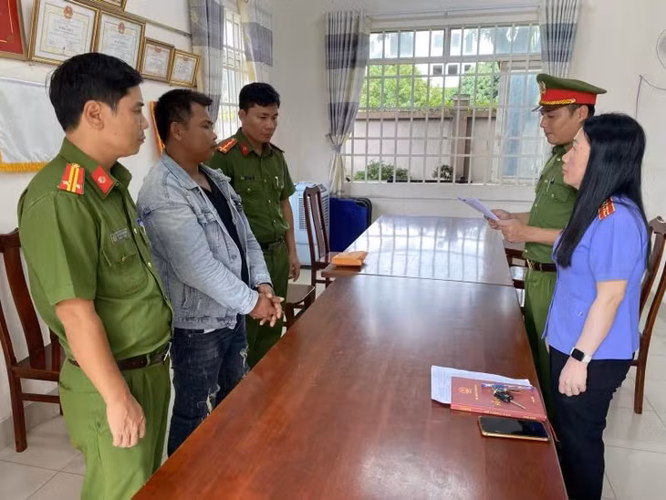 Cơ quan điều tra tống đạt quyết định khởi tố, lệnh bắt tạm giam đối với 1 trong 4 bị can. (Ảnh: Báo Công an Nhân dân)