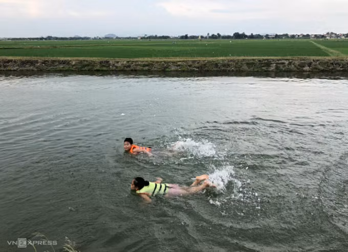 Trẻ em ở học bơi trên kênh đào thủy lợi có sự giám sát của người lớn. Ảnh: Hồng Chiêu