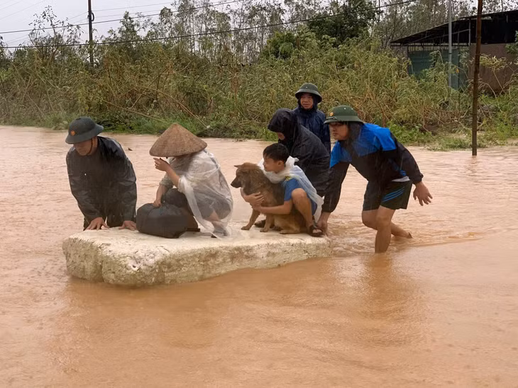 Cán bộ, chiến sĩ Đồn Biên phòng Cửa khẩu Hoành Mô hỗ trợ người dân xã Hoành Mô ra khỏi vùng bị nước chia cắt do mưa lũ đến nơi an toàn. Ảnh: La Nhung CTV