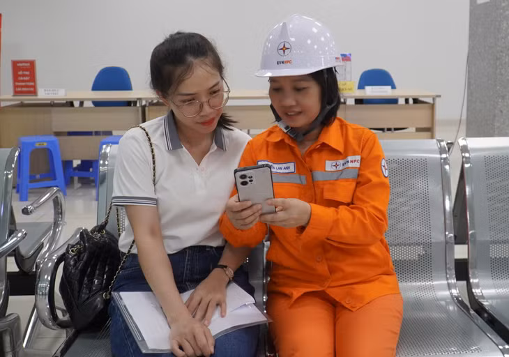 Công nhân Điện lực Hạ Long hướng dẫn người dân sử dụng APP chăm sóc khách hàng. Ảnh: Ngọc Lan