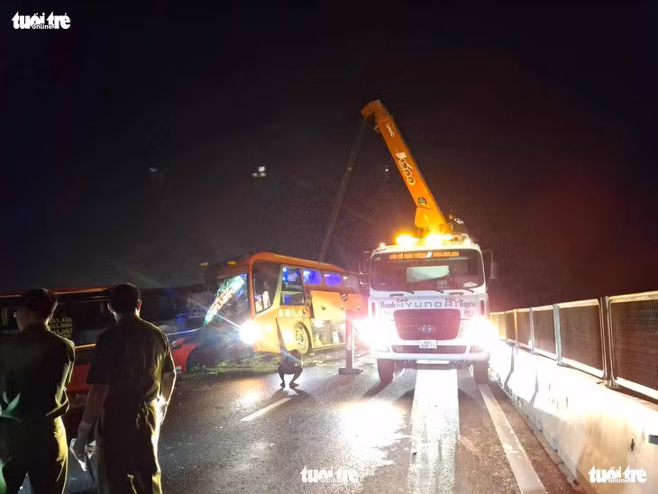 Xe Phương Trang vừa được cẩu nhích ra khỏi xe Hồng Sơn để các lực lượng cứu hộ lên tìm kiếm các vật dụng, giấy tờ tùy thân nạn nhân - Ảnh: ĐỨC TRONG