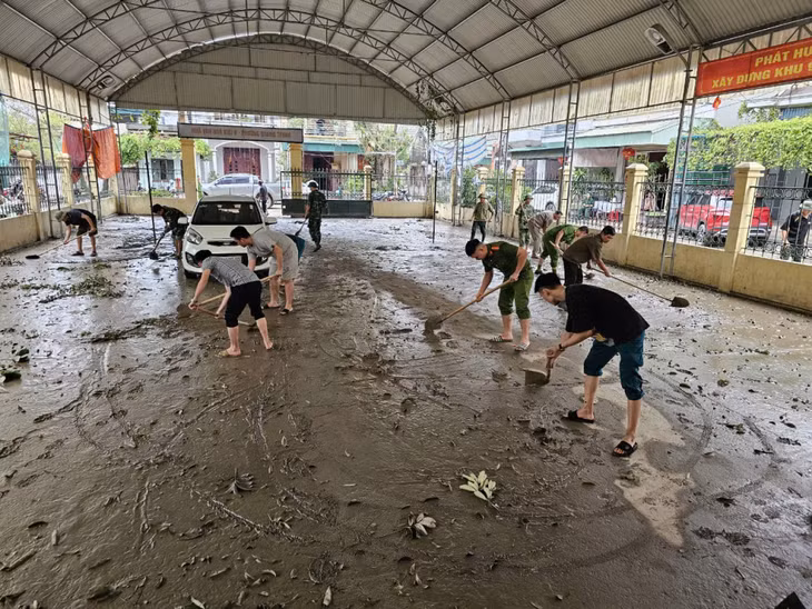 Bộ đội, công an hỗ trợ người dân khu 9, phường Quang Trung khắc phục hậu quả sau lũ.
