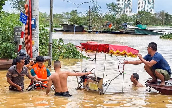 Người Hà Nội bơi trong dòng nước lũ ở sông Hồng để vớt tài sản - Ảnh: PHẠM TUẤN