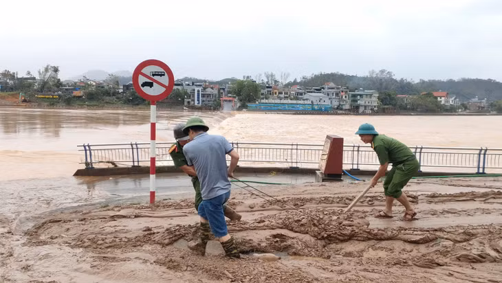 Cán bộ, chiến sĩ công an thị trấn tham gia dọn vệ sinh môi trường, bùn đất sau khi lũ rút.