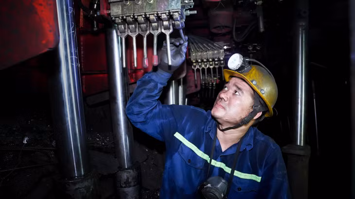 Trước mỗi ca làm việc, anh luôn kiểm tra kỹ vị trí thi công, trực tiếp trao đổi với anh em đồng đội về phương án củng cố lò, xúc dọn đất đá, khoan gương và phân công người nạp mìn. Ảnh chụp Công tác khoan - nổ mìn tại gương lò chợ giá thủy lực di động dạng khung ZH1600/2400.